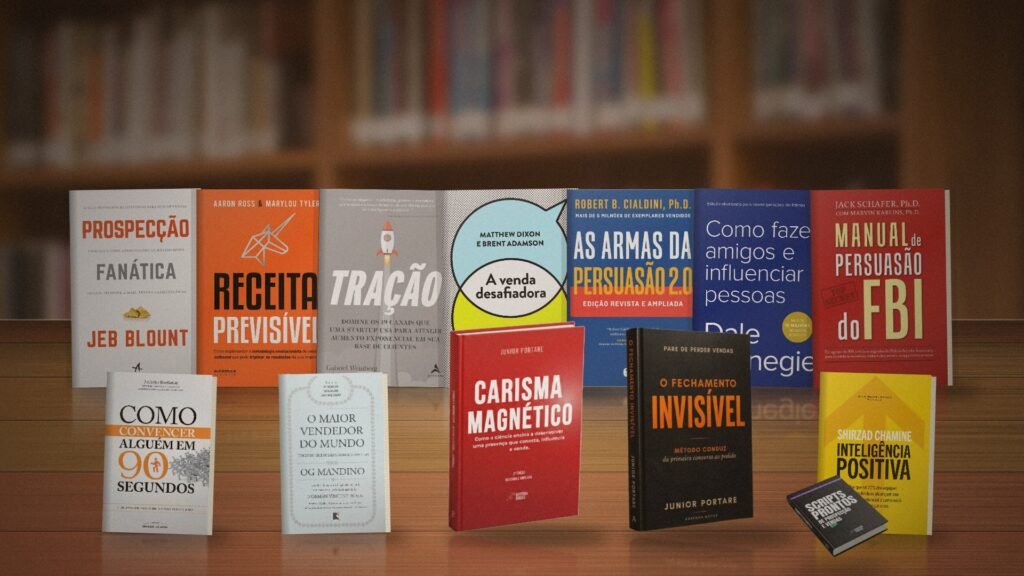Melhores livros de vendas: 13 capas de livros sobre prospecção, persuasão e fechamento organizadas em um balcão de madeira de livraria